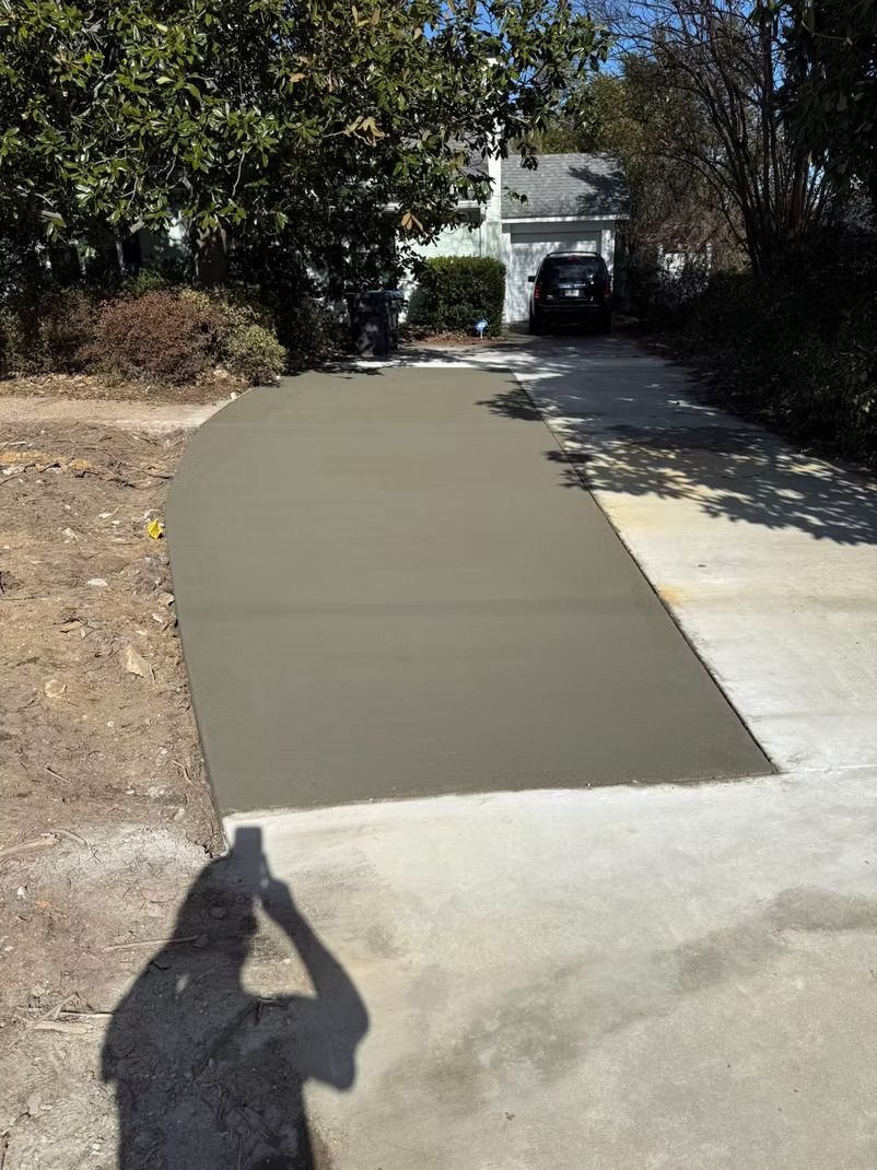 Newly poured concrete driveway extension, light gray, connecting to older driveway.