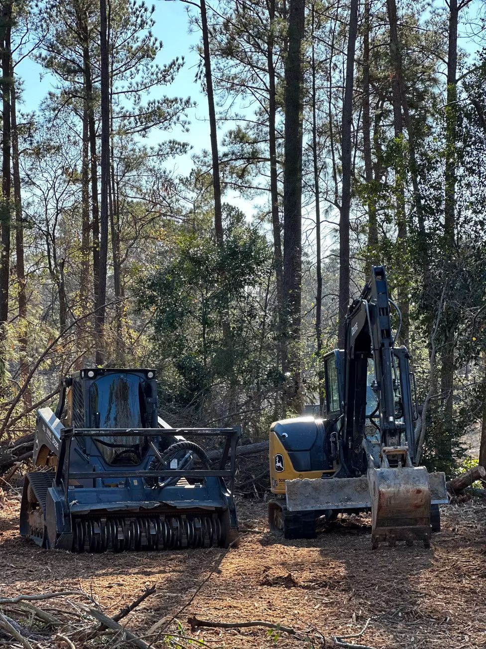 A tracked brush cutter and excavator in a forest clearing, ready for land clearing.