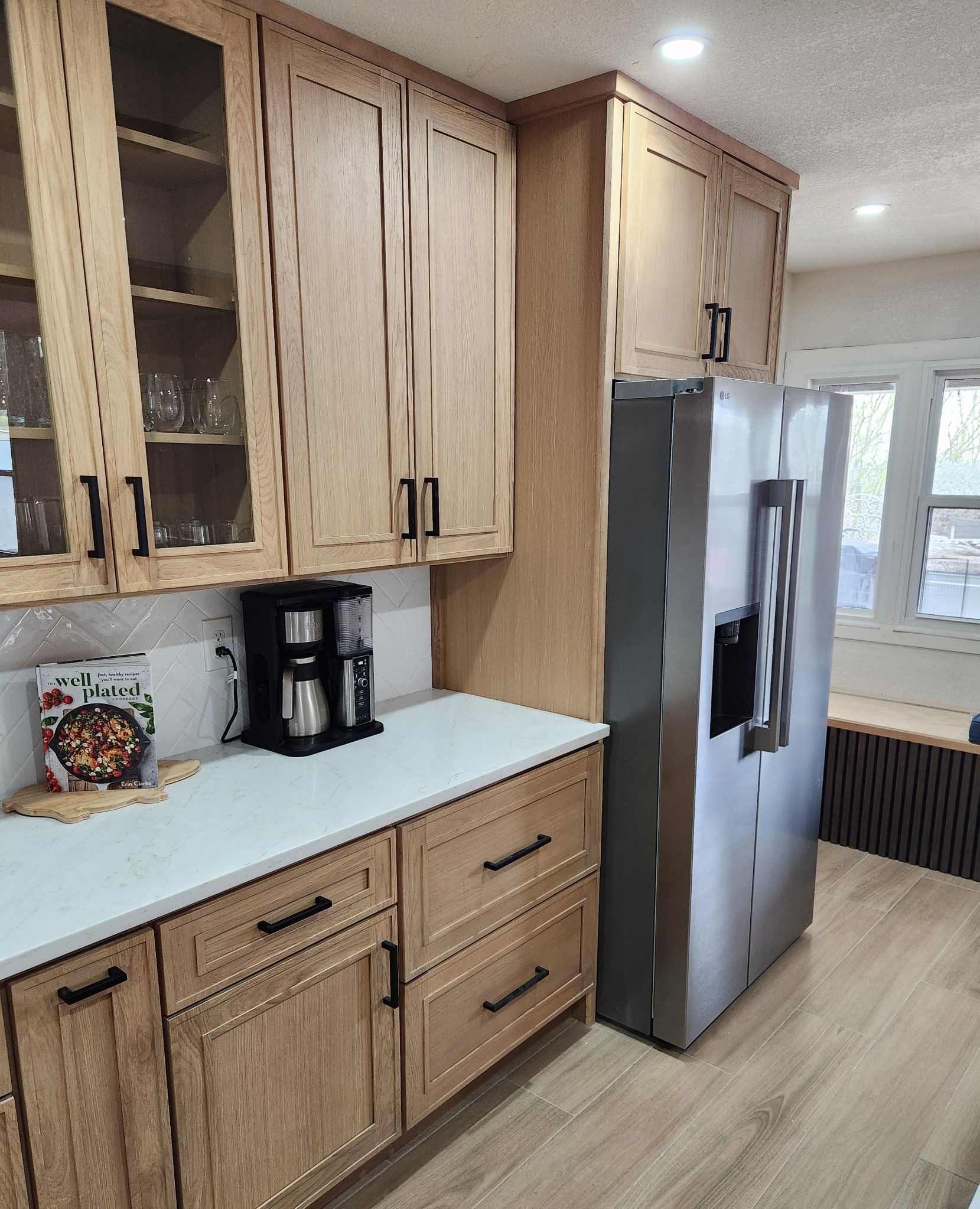 Kitchen with light wood cabinets, white countertops, and stainless steel refrigerator.