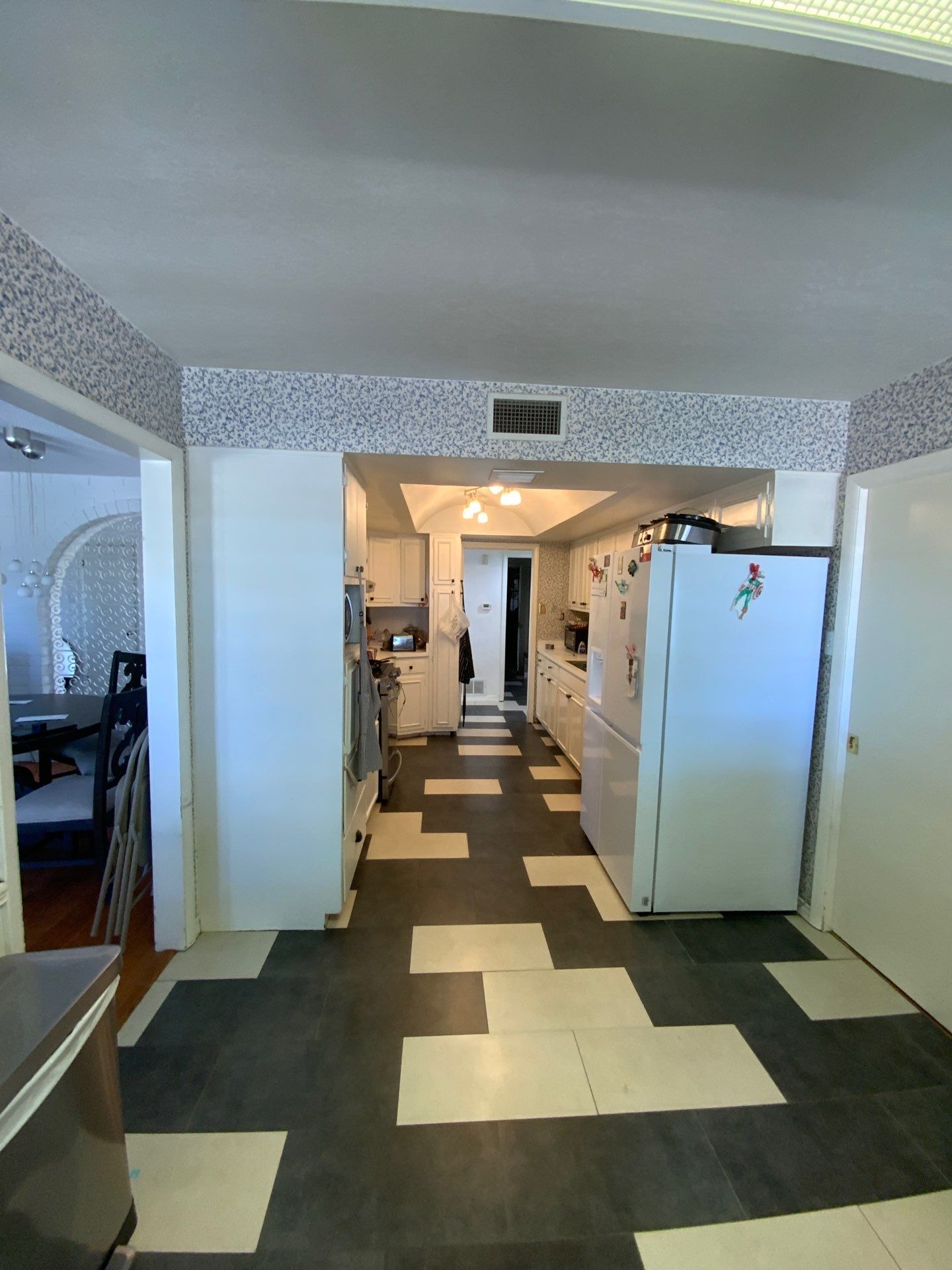 Kitchen with patterned floor, white appliances, and a hallway leading to another room.