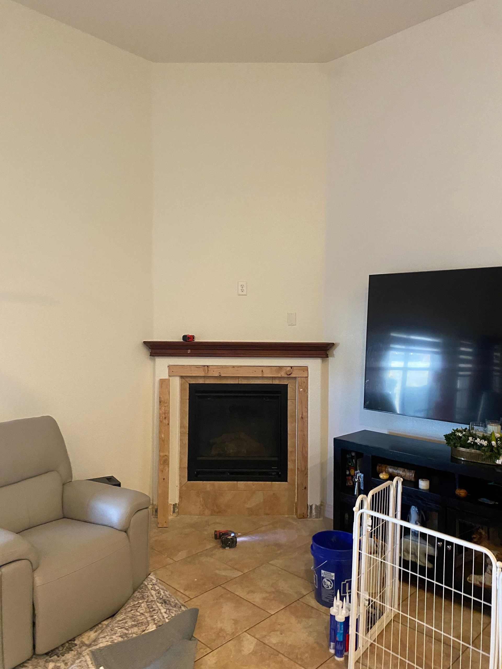 Fireplace with brown mantel, beige tile floor, and large TV.