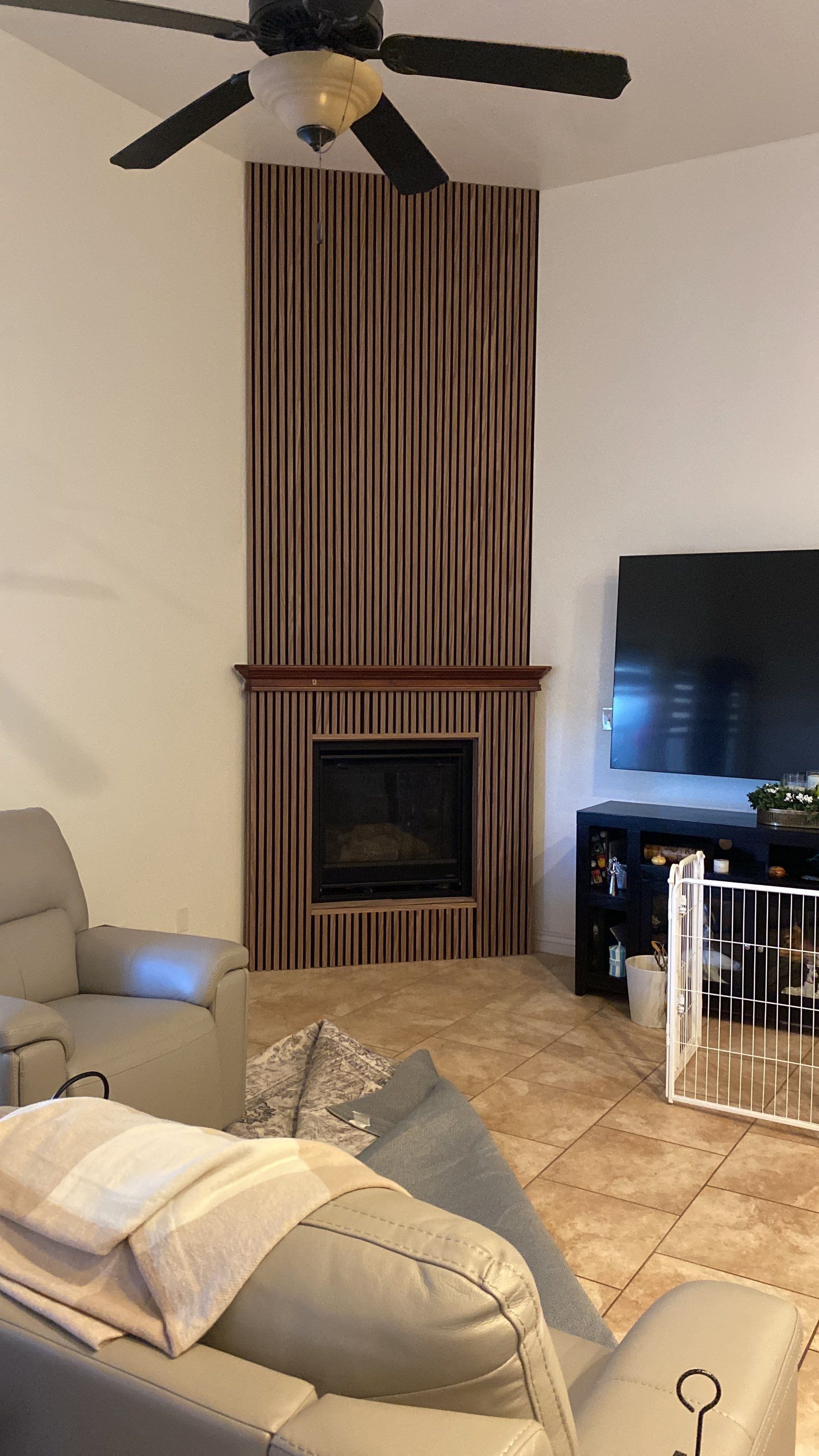 Living room with brown fireplace, TV, recliner, and ceiling fan.