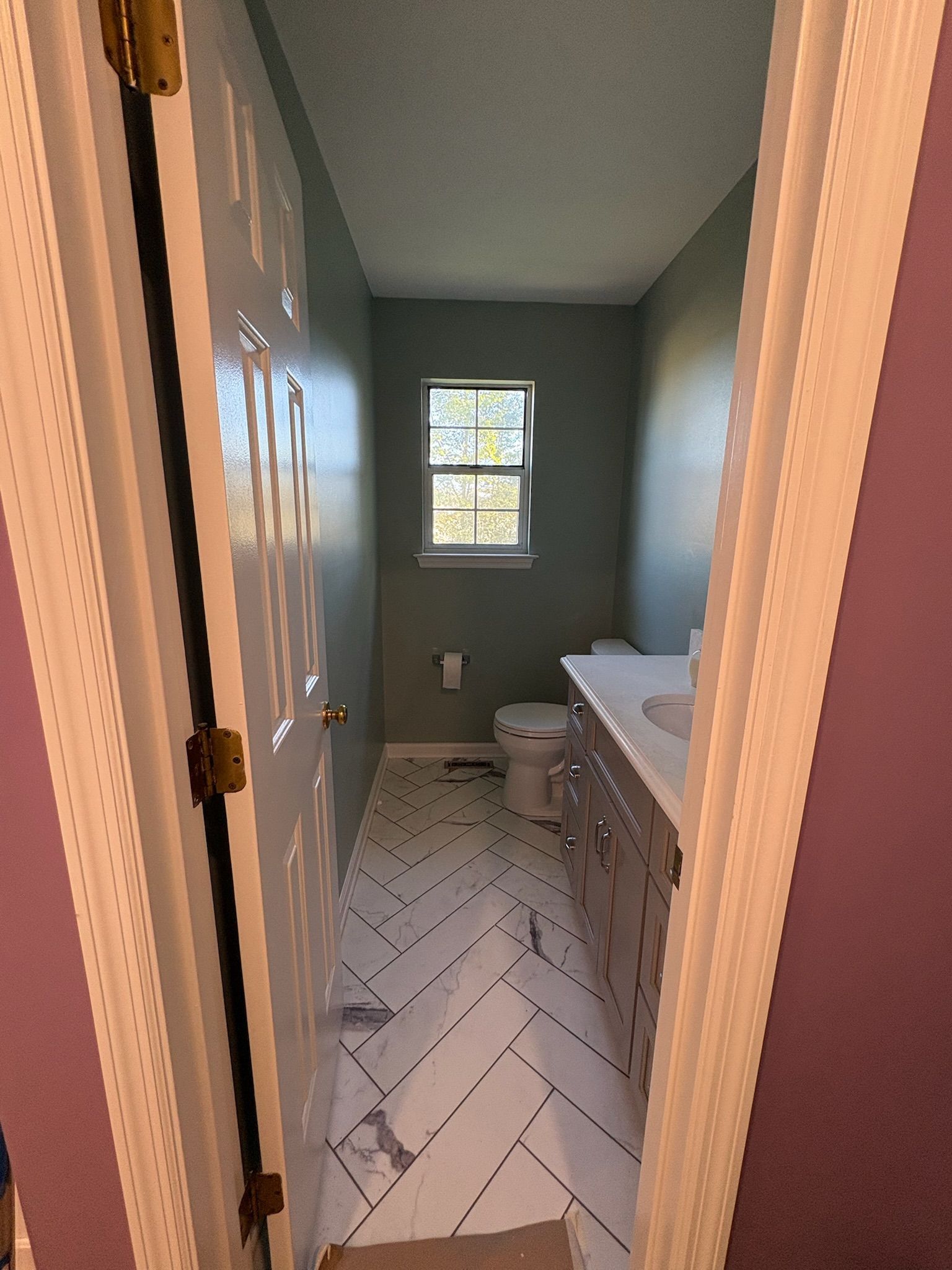 A bathroom with a toilet , sink , and window