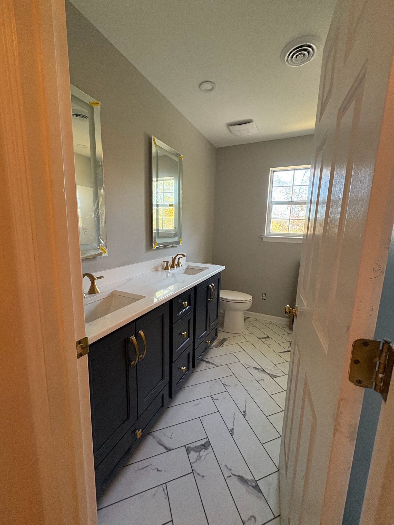 A bathroom with two sinks , a toilet , and a window.