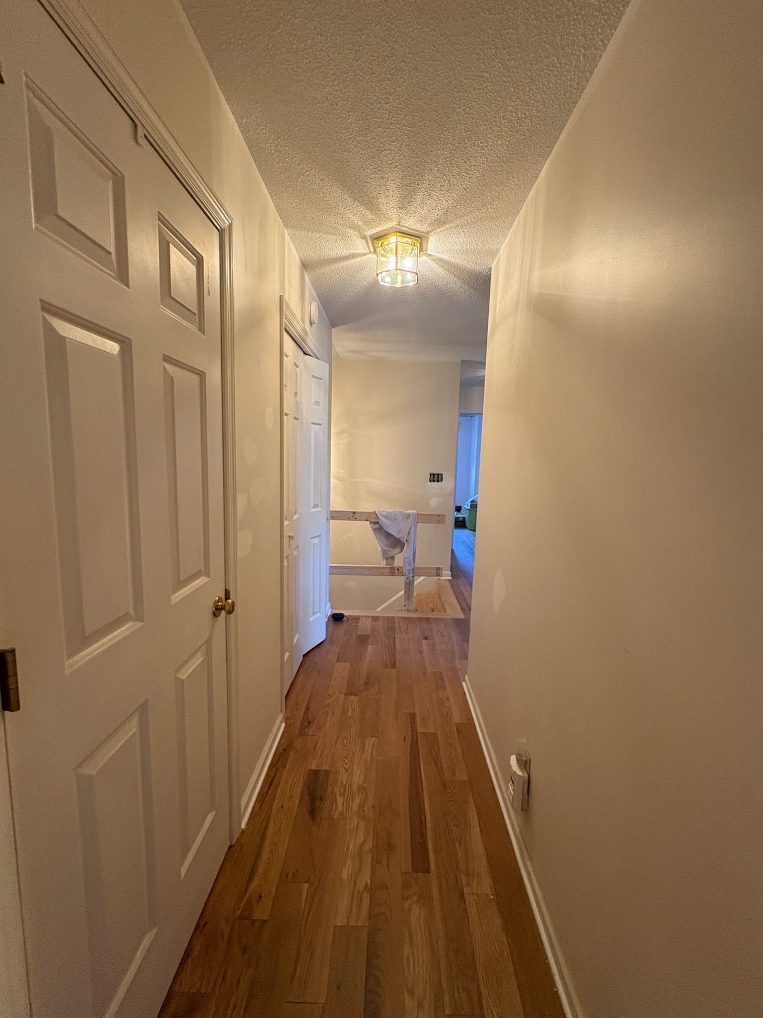 A long hallway with hardwood floors and white walls in a house.
