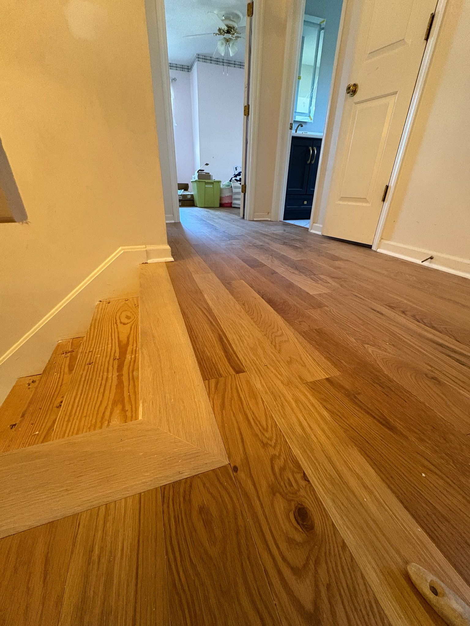 A hallway with a wooden floor and stairs leading to a living room.