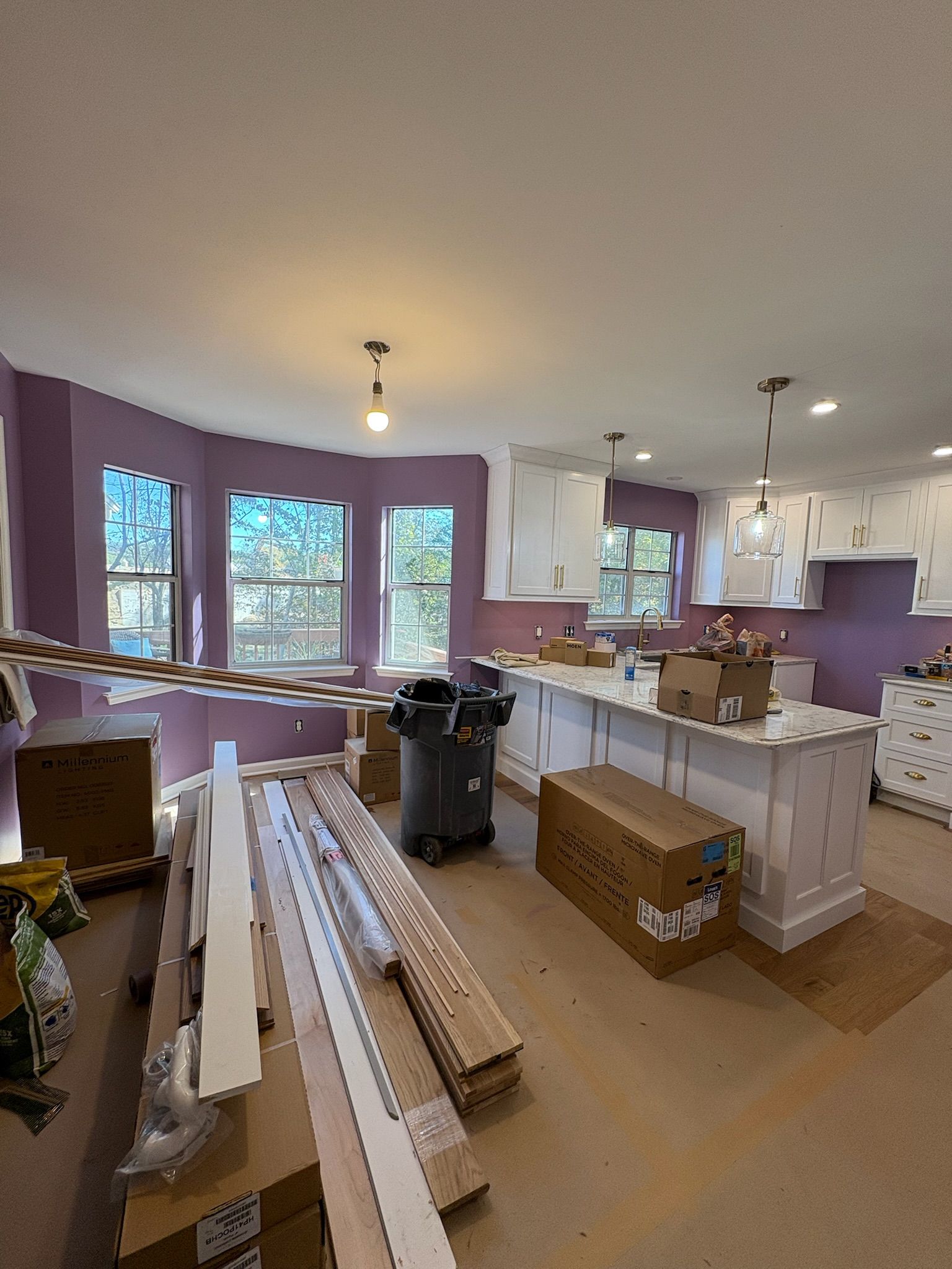 A kitchen is being remodeled with purple walls and white cabinets.