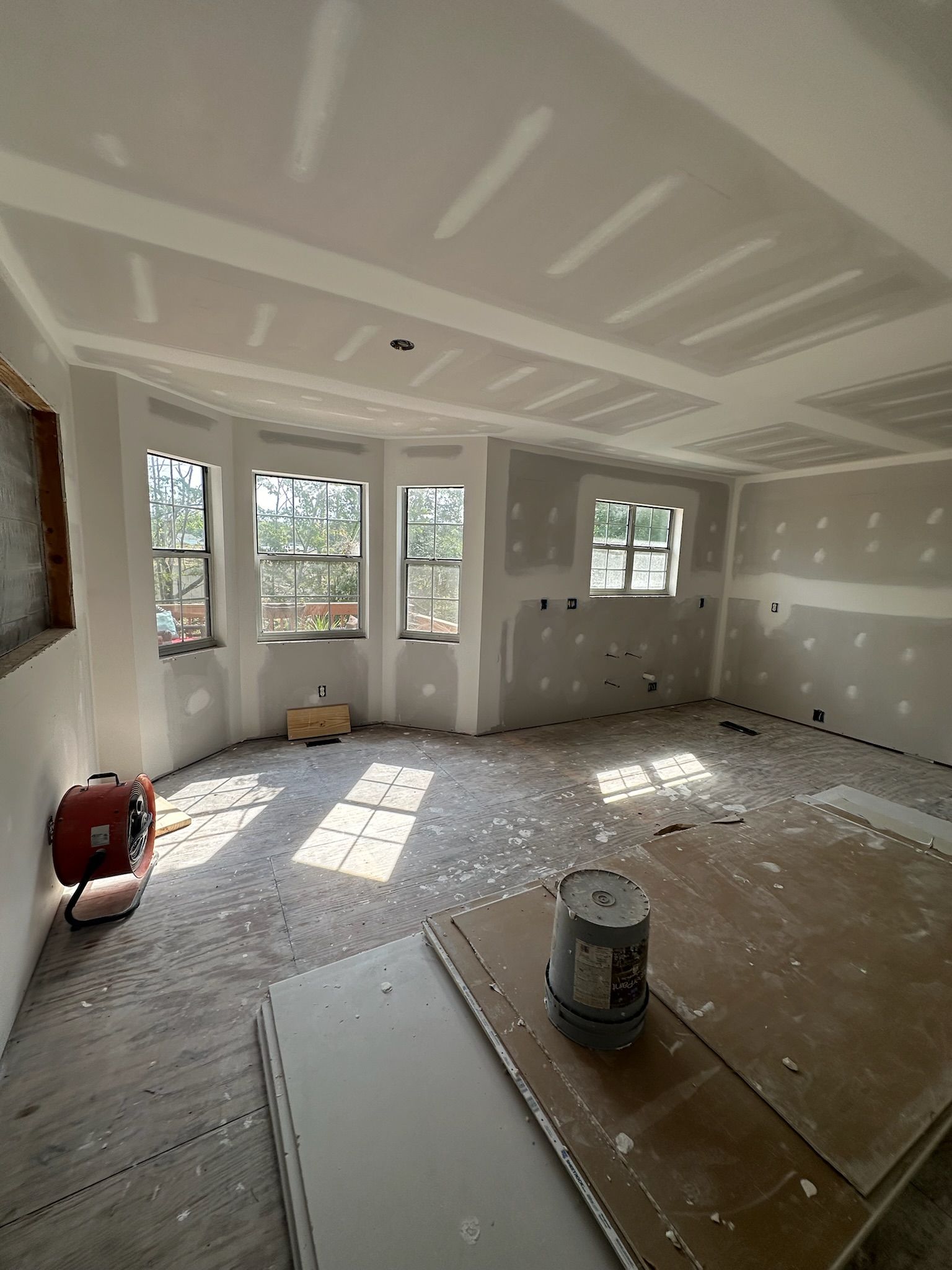 An empty room with a bucket of paint on the floor.
