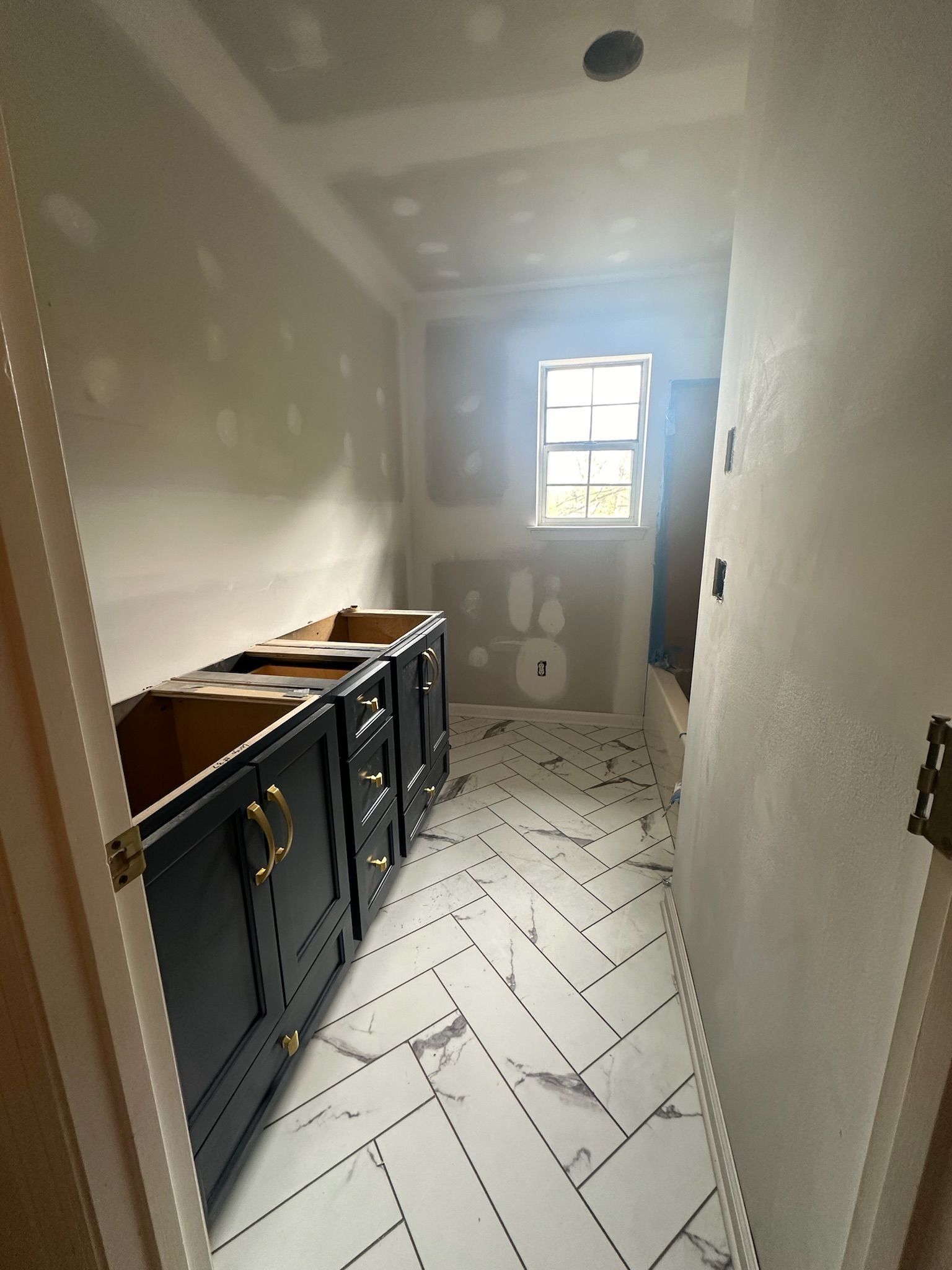 A bathroom under construction with black cabinets and white tile floors.
