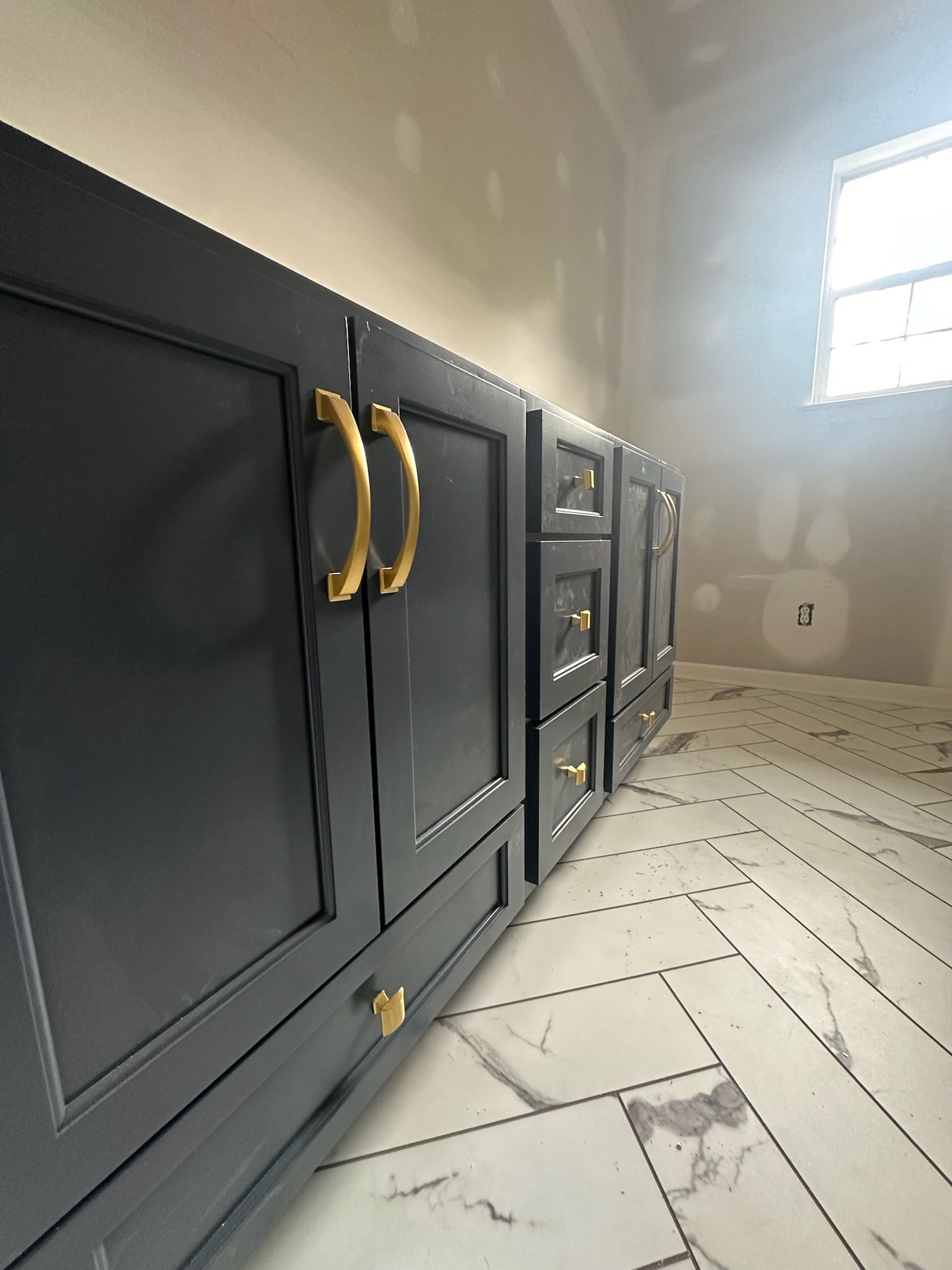 A bathroom with black cabinets and gold handles is being remodeled.