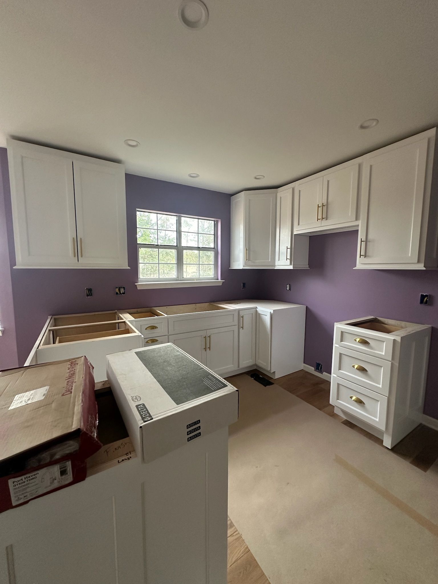 A kitchen under construction with purple walls and white cabinets