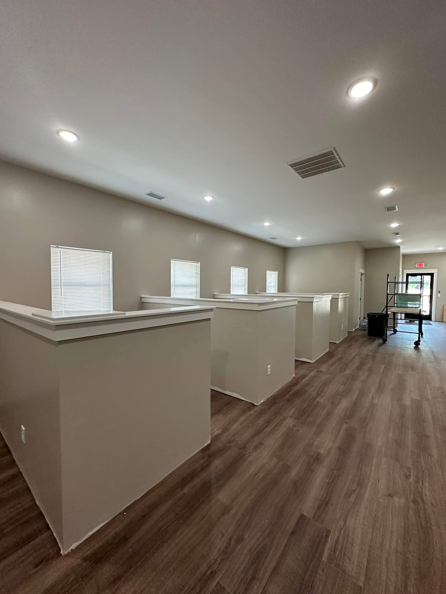 A large room with a lot of windows and hardwood floors.