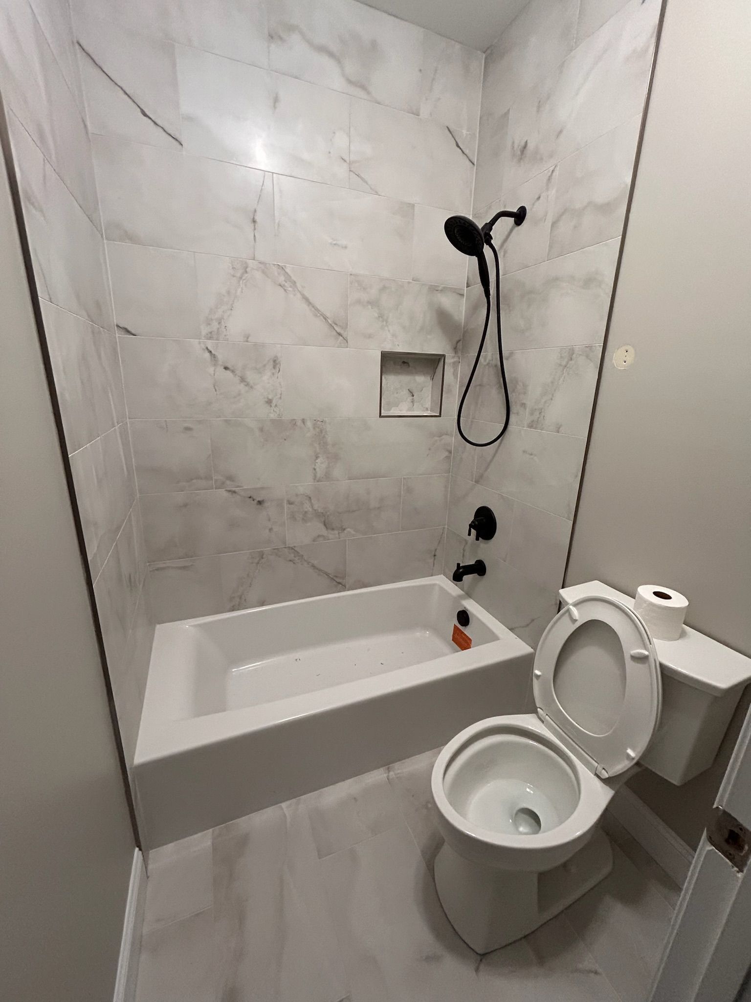 A bathroom with a toilet , bathtub and shower.