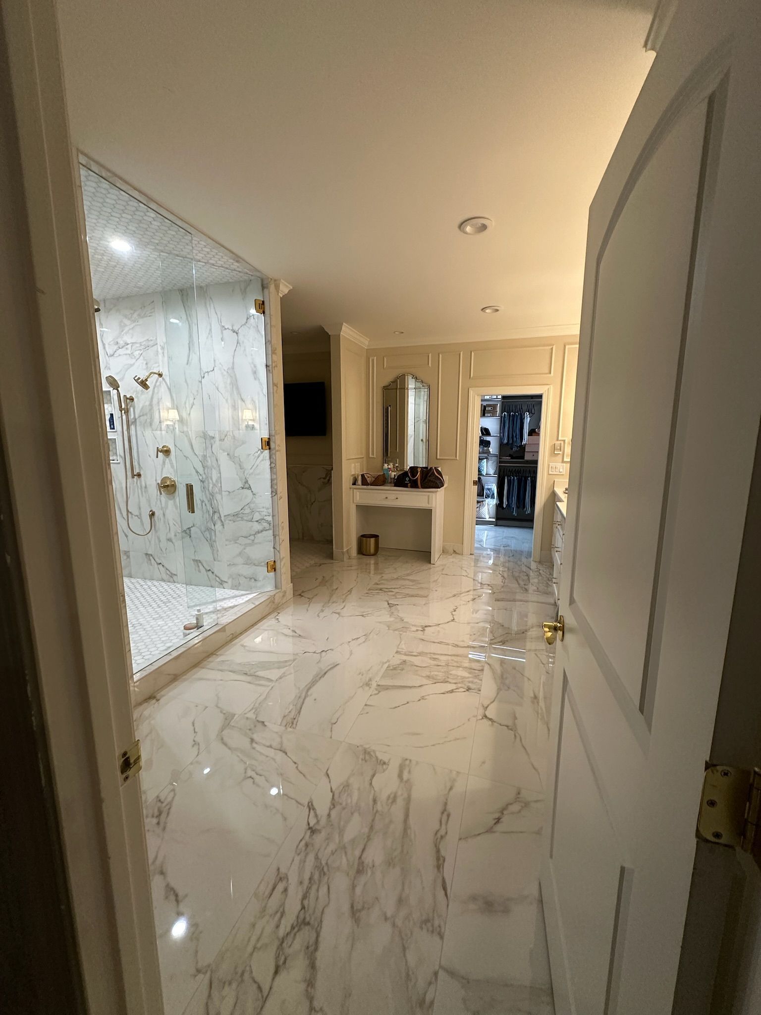A bathroom with marble floors and a walk in shower.