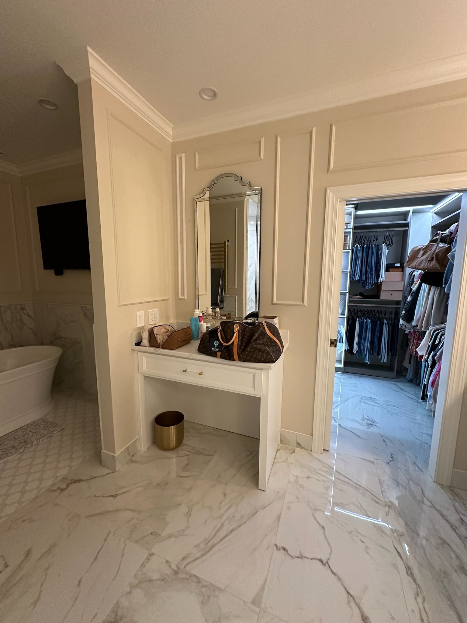 A bathroom with a vanity , mirror and walk in closet.