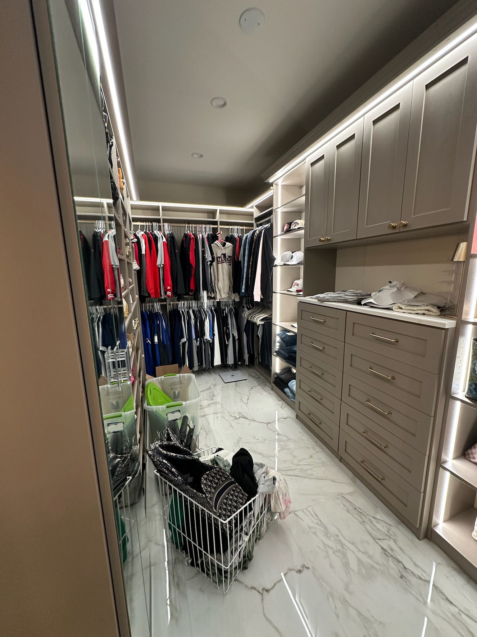 A walk in closet filled with lots of clothes and dressers.