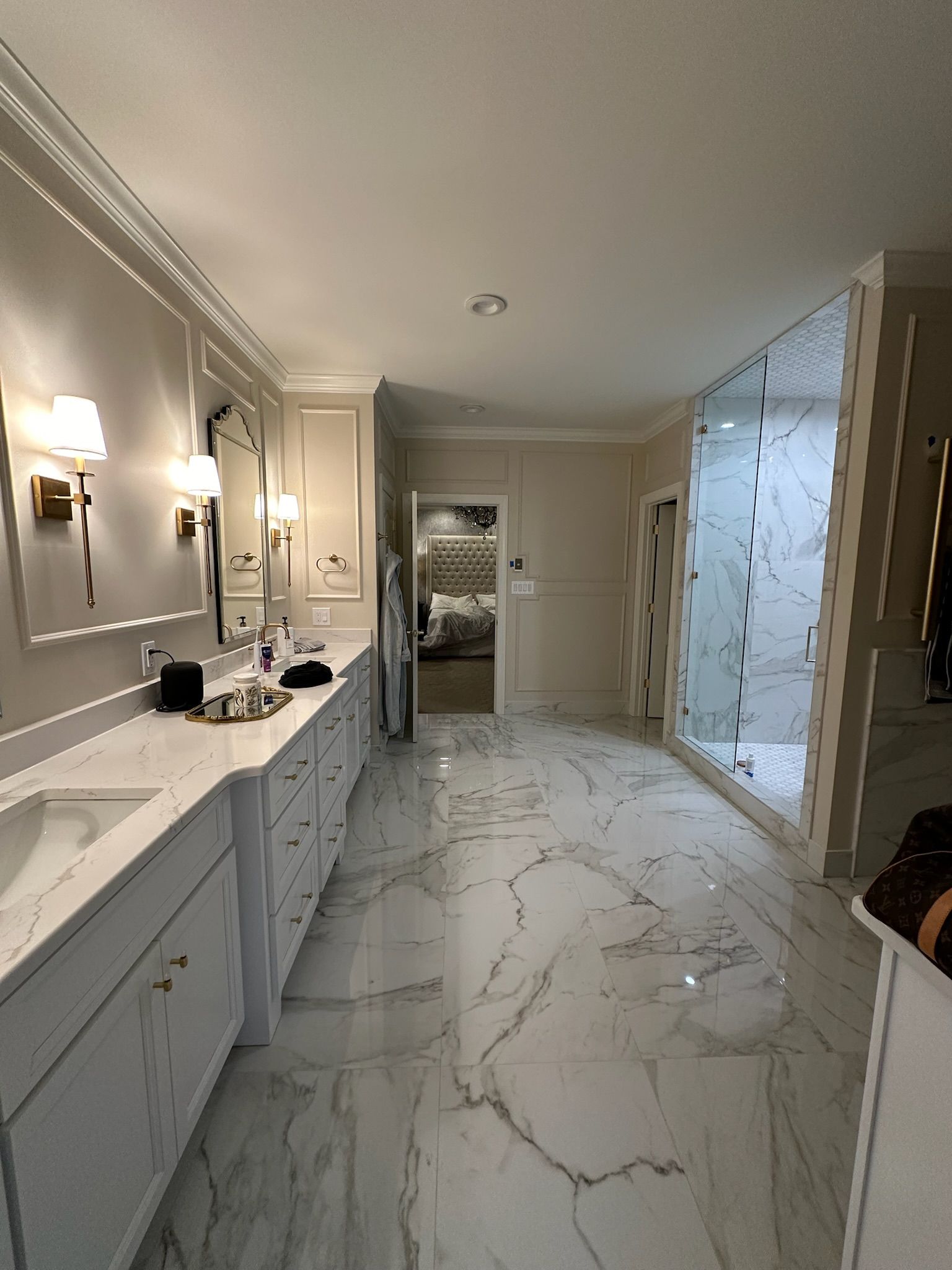 A bathroom with marble floors , sinks , mirrors and a walk in shower.