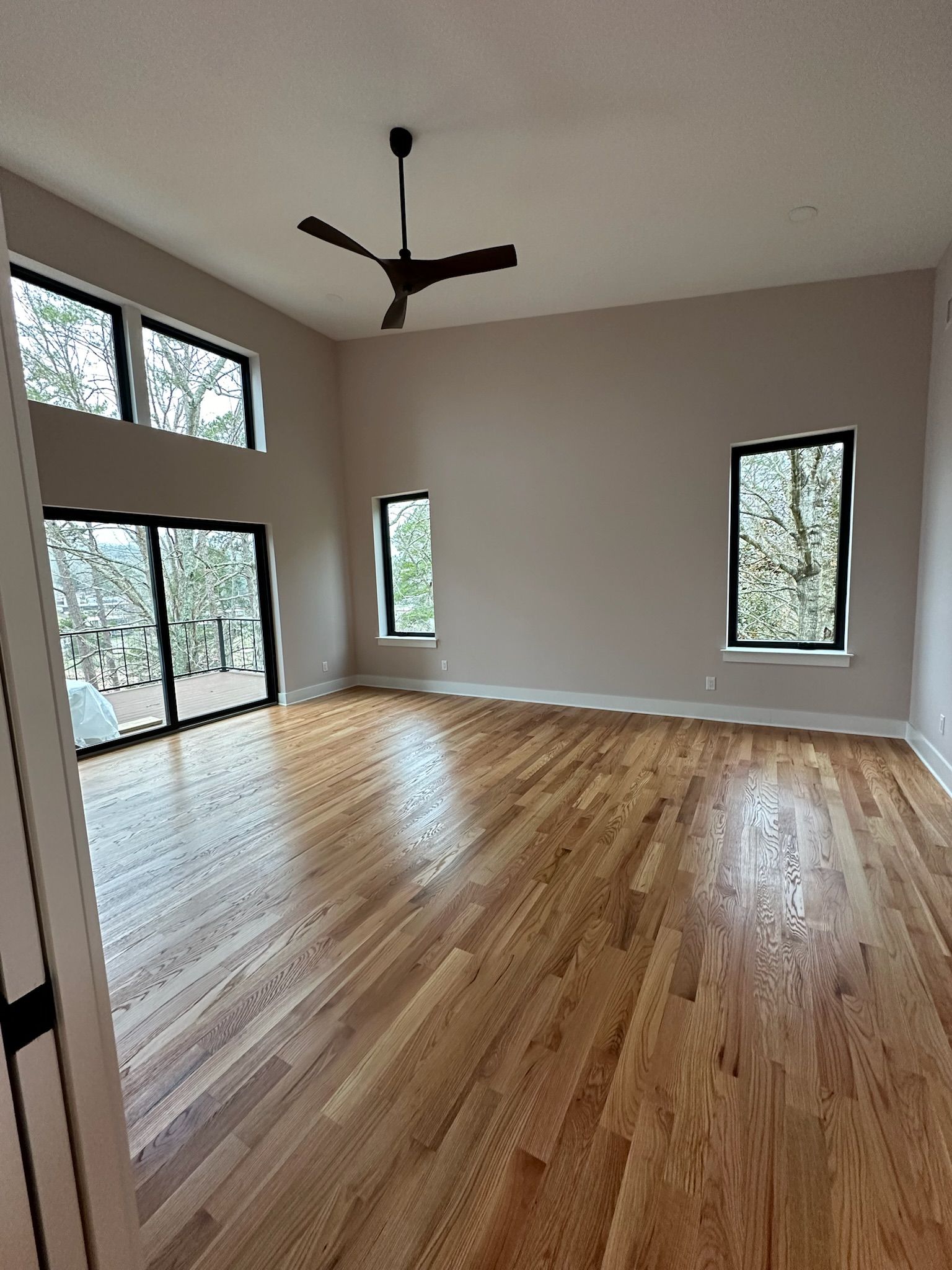 An empty living room with hardwood floors and a ceiling fan.