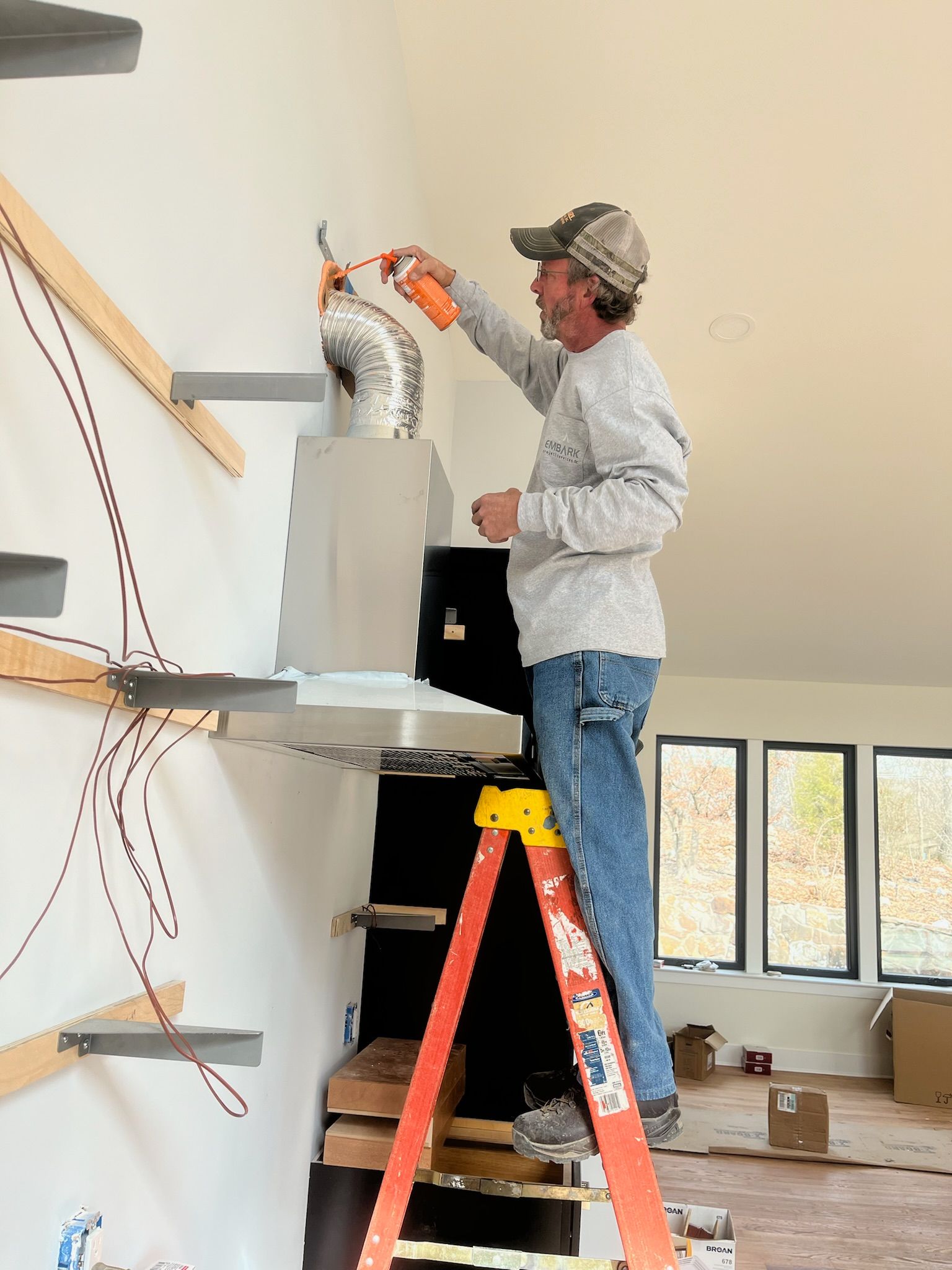 A man is standing on a ladder working on a wall