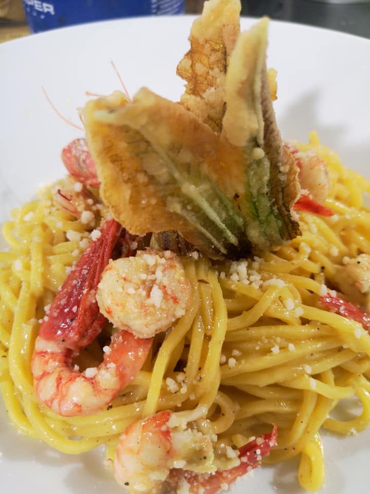 Una ciotola di cibo con calamari e pomodori su un tavolo.