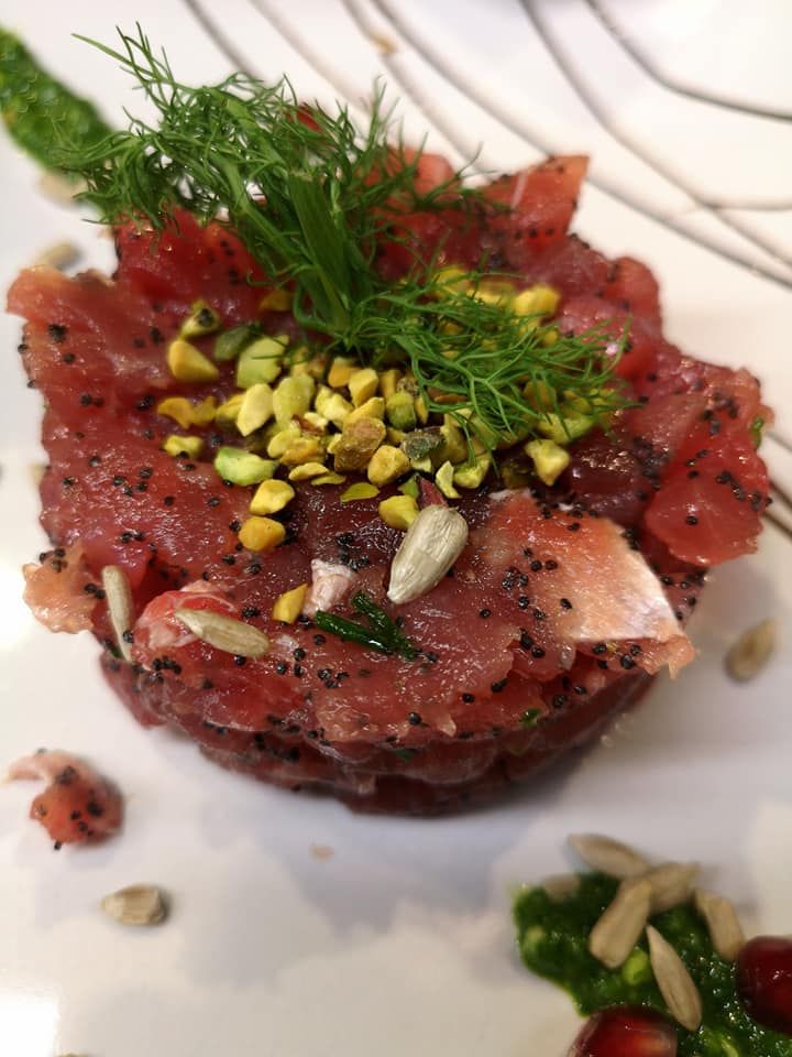 Un piatto bianco con verdure e basilico su un tavolo di legno.