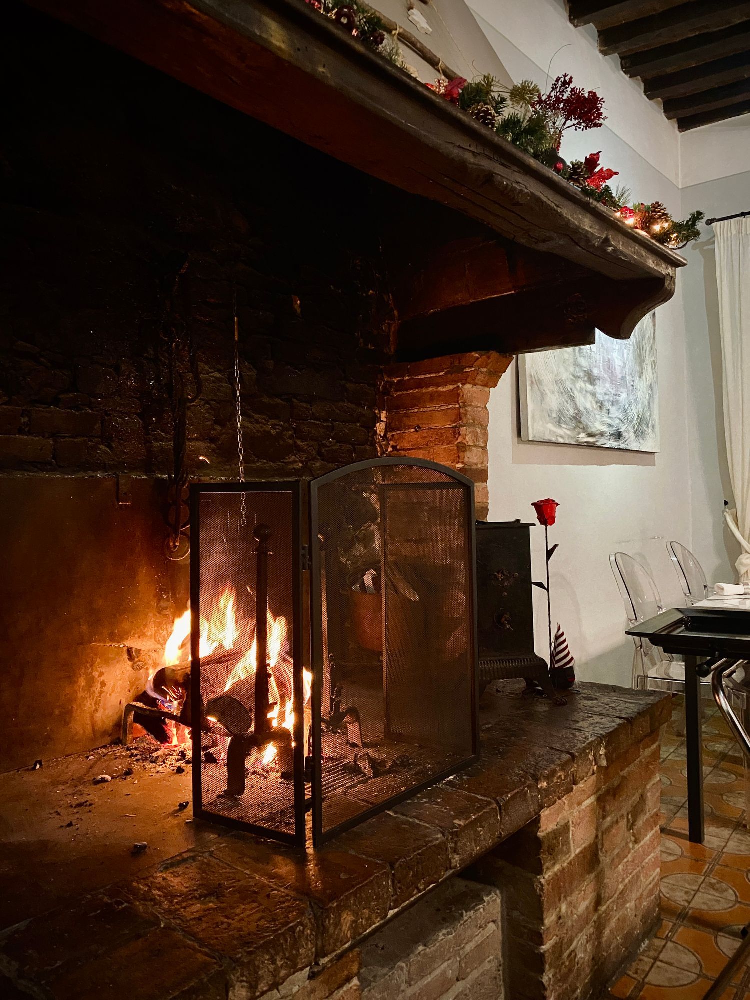 Camino con ceppi ardenti, paravento nero, cornice in mattoni rossi, ghirlanda e rosa.