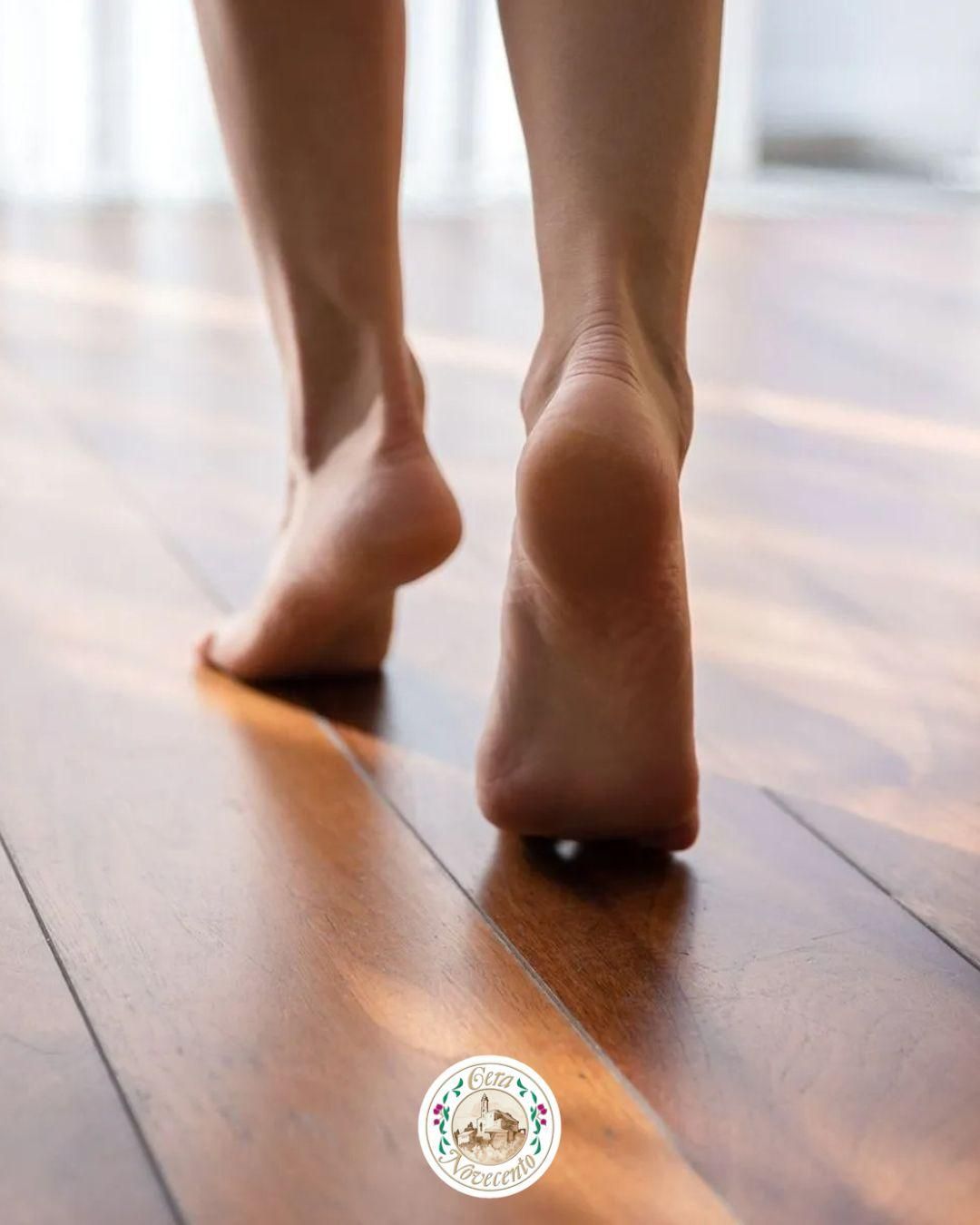 Piedi nudi che camminano su un pavimento di legno, visti da dietro.