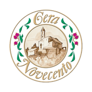 Un logo circolare raffigurante lo schizzo di un villaggio italiano con un campanile, circondato da foglie verdi e fiori color magenta.