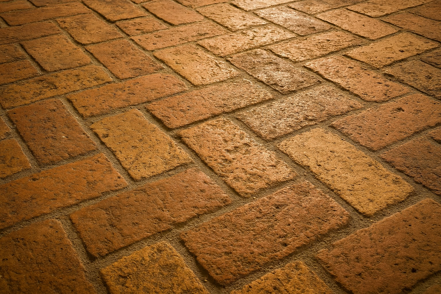 Pavimentazione in mattoni a spina di pesce, con diverse tonalità di marrone.