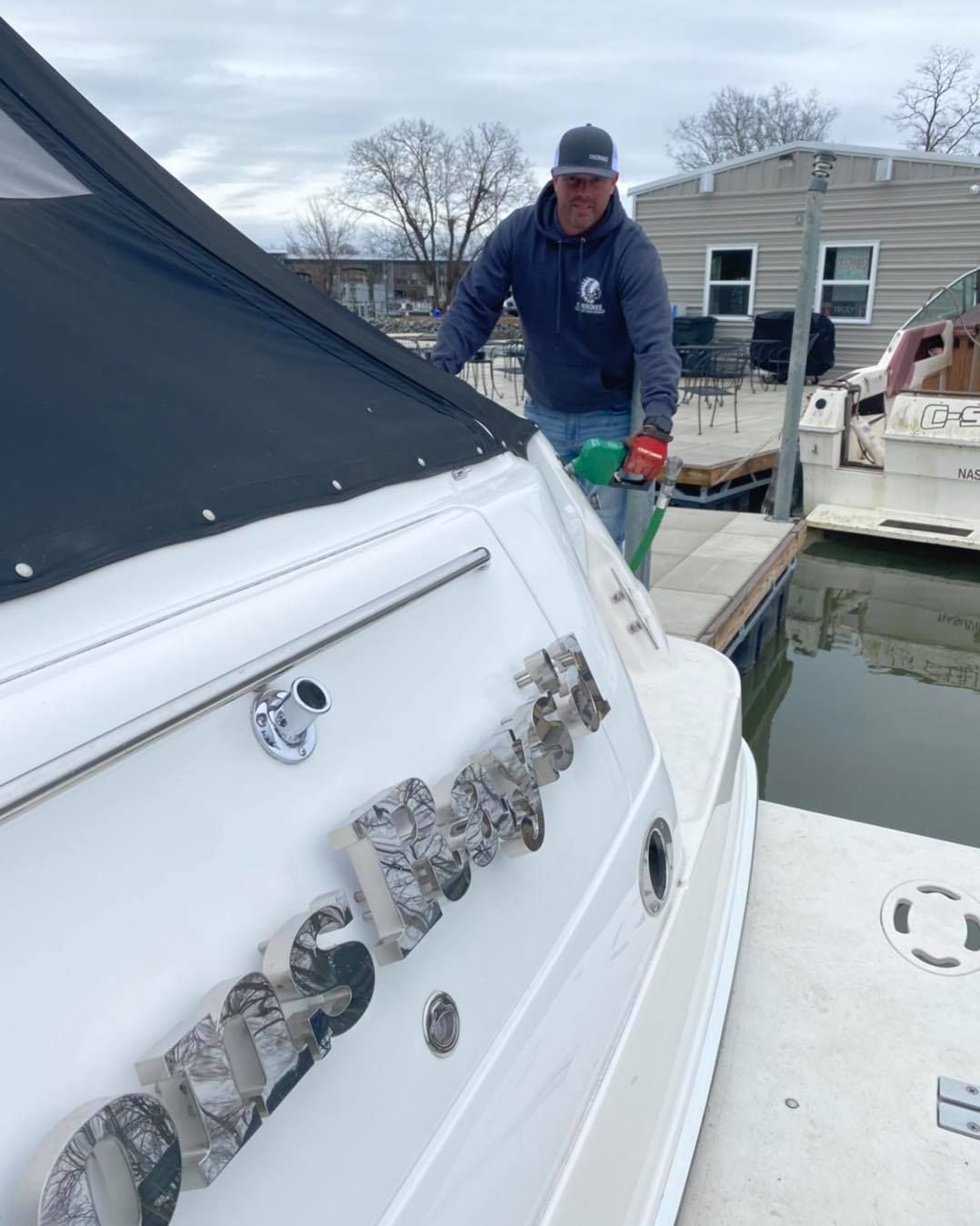 A man is standing next to a boat that says ' oasis ' on it