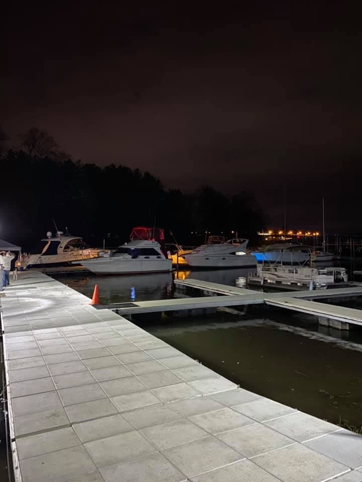 A group of boats are docked at a marina at night.