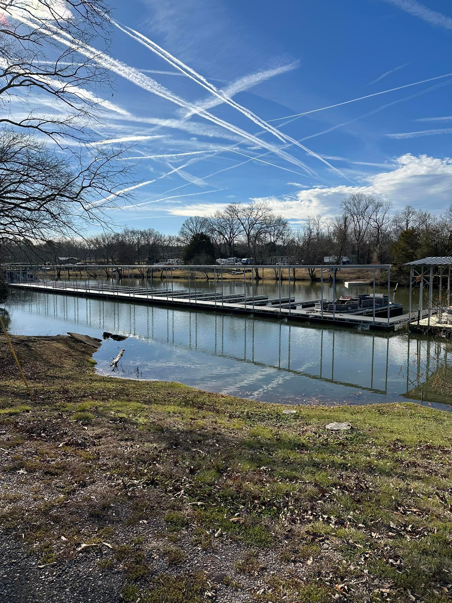 A row of boats are docked at a marina on a sunny day.