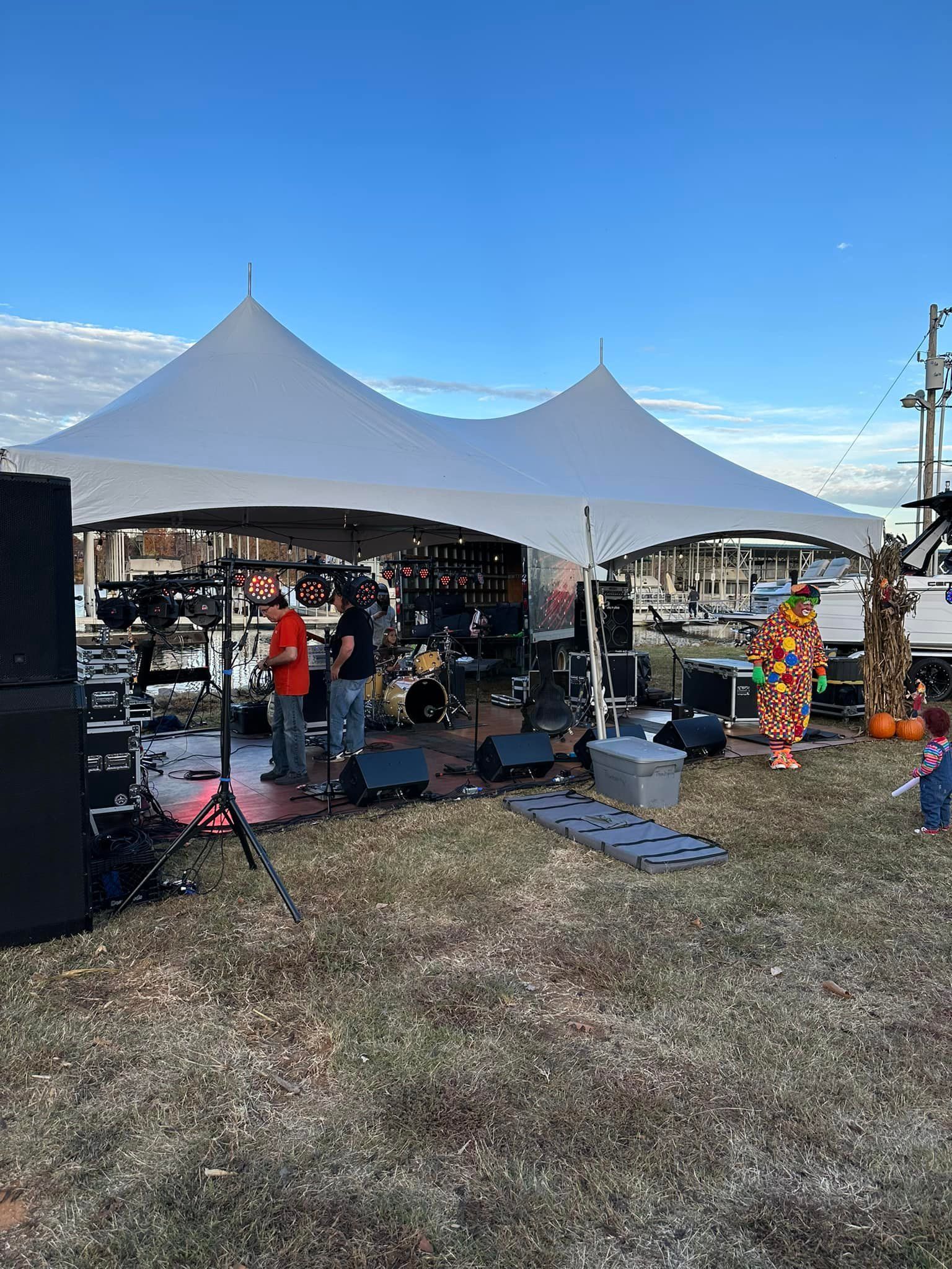 A group of people are standing under a tent in a field.
