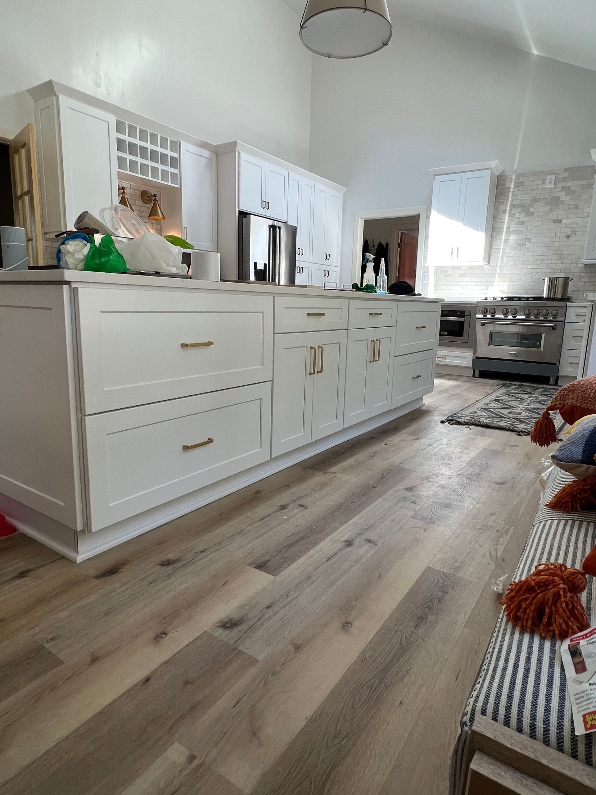 A bright white kitchen with a large island and wood-look flooring.
