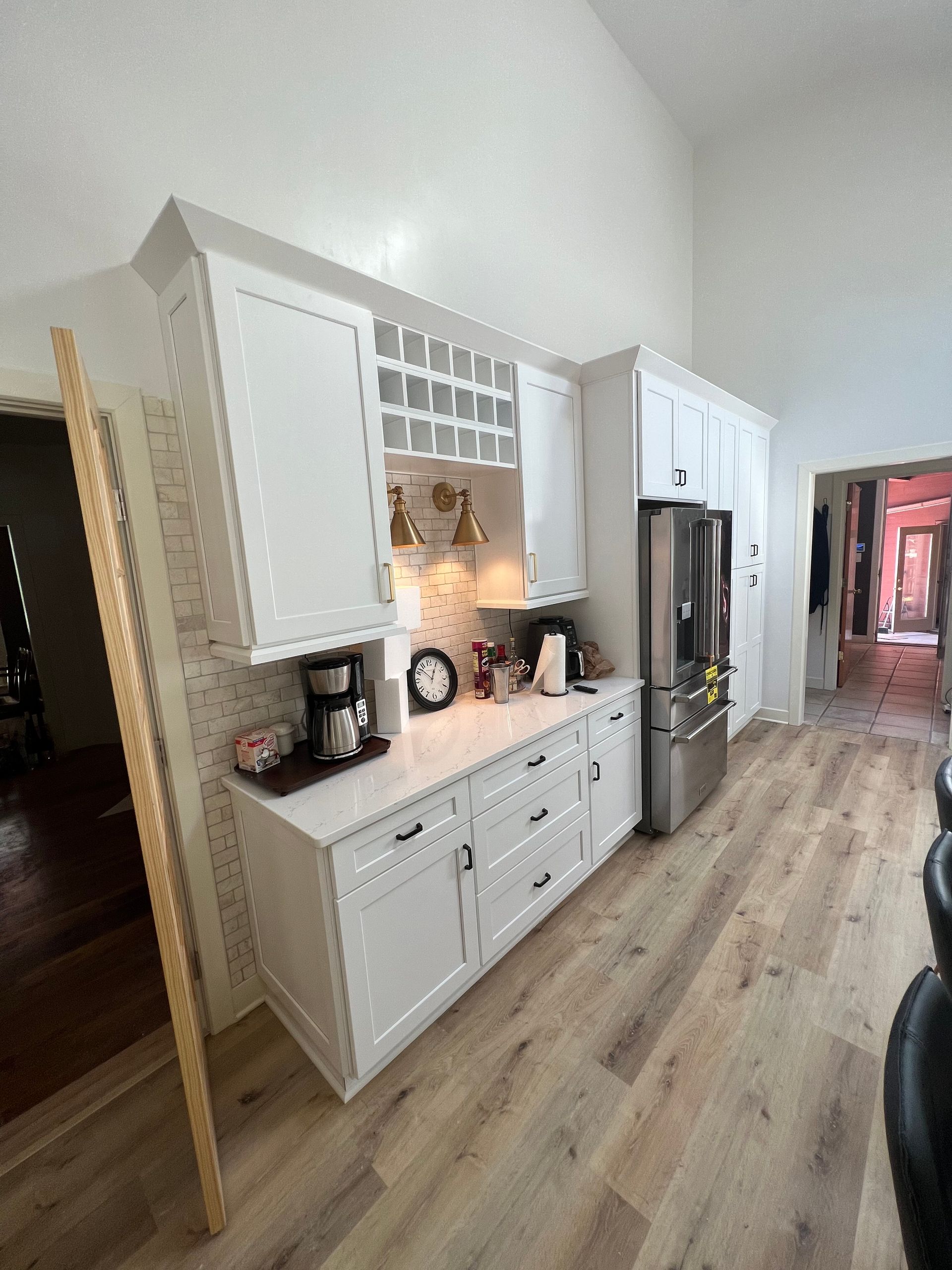 Woman in straw hat smiles, holding wine glass near a lake.