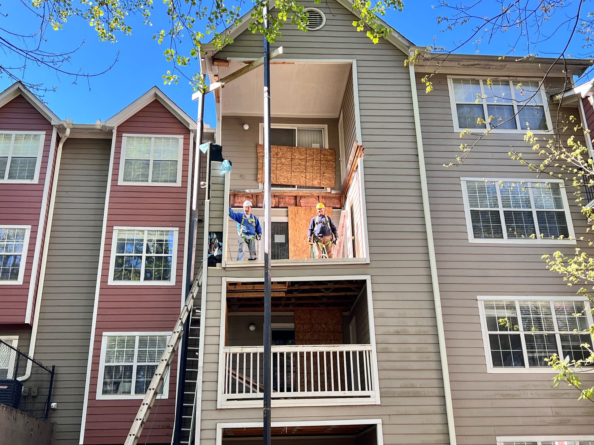 Workers on scaffolding repairing exterior wall of multi-story building.