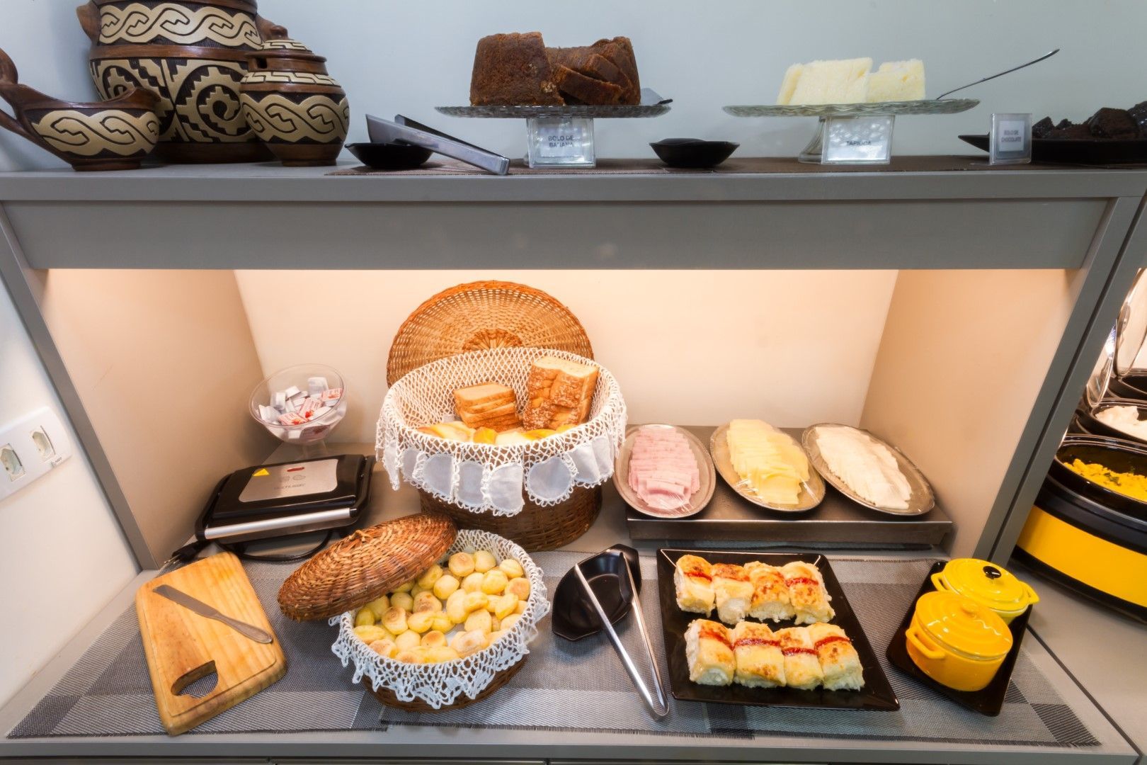 Uma vitrine repleta de uma variedade de alimentos, incluindo pão e queijo.