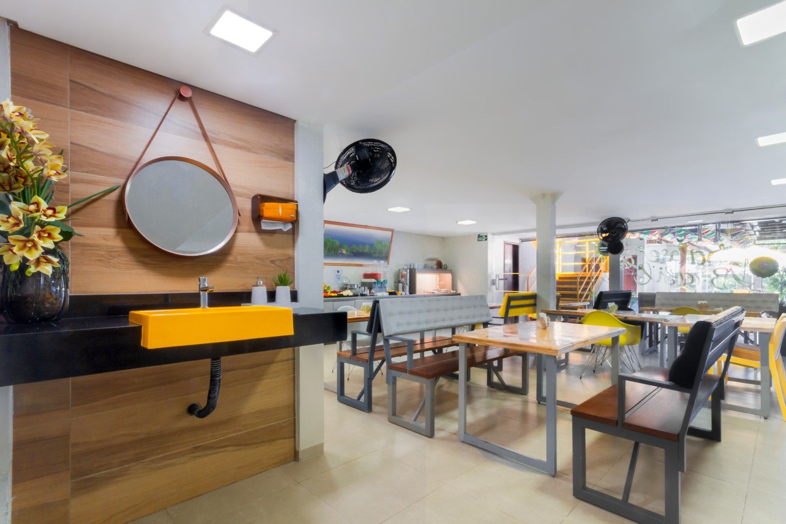 Uma sala com mesas, cadeiras, uma pia e um espelho.