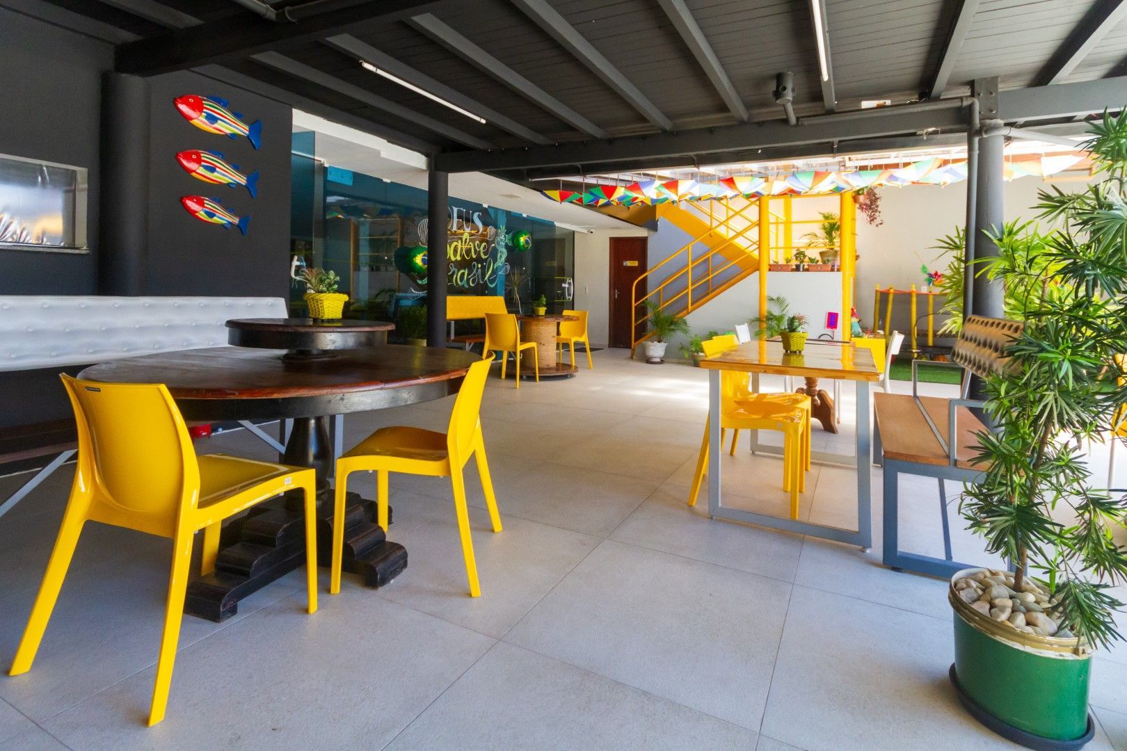 Um restaurante com cadeiras e mesas amarelas e uma planta em vaso.