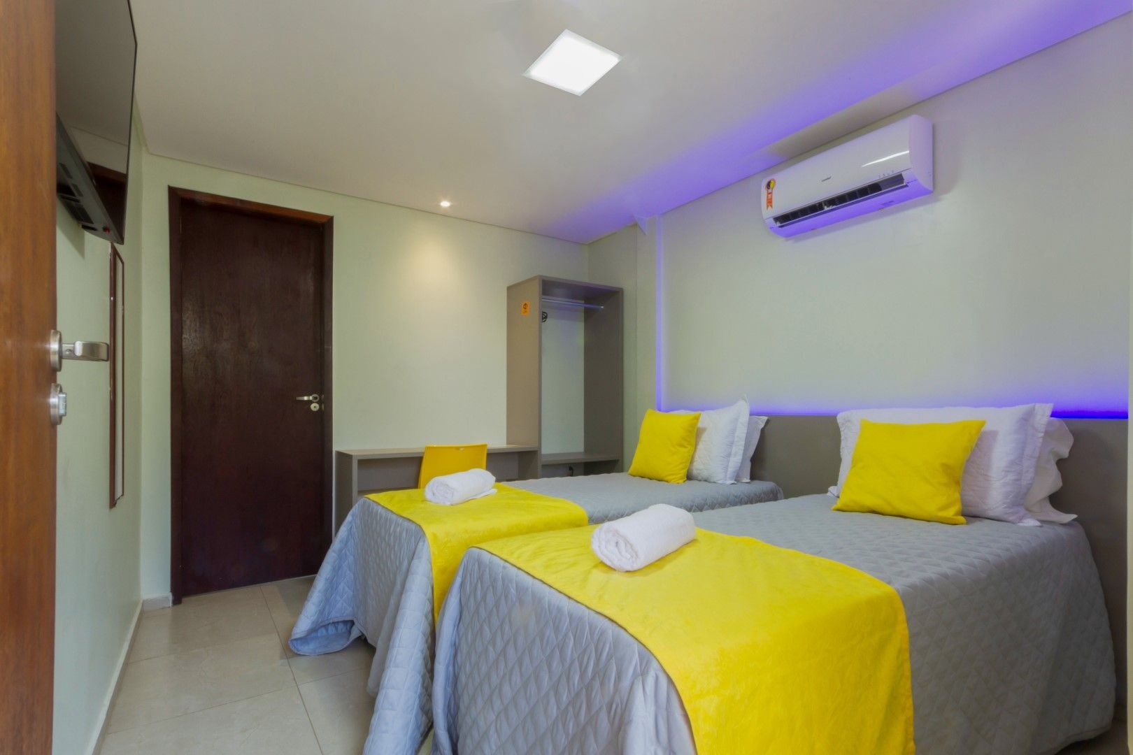 Um quarto de hotel com duas camas e uma televisão.