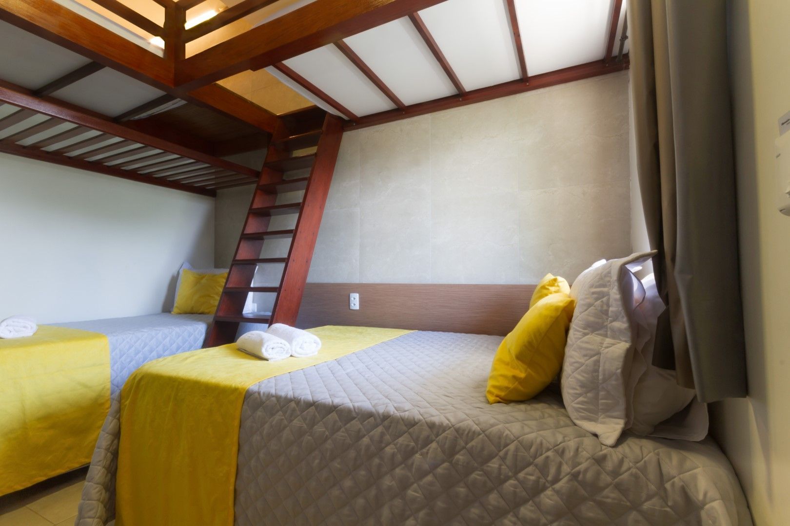 Um quarto de hotel com beliches e uma escada.