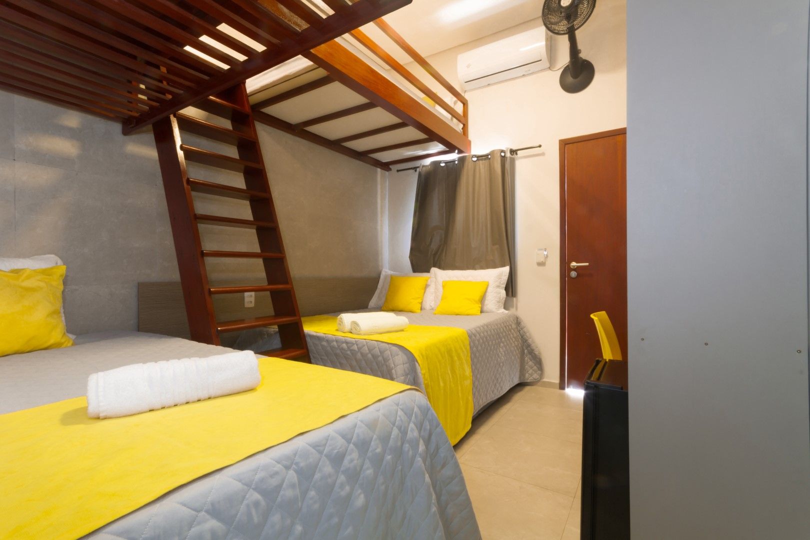 Um quarto de hotel com duas camas e um beliche.