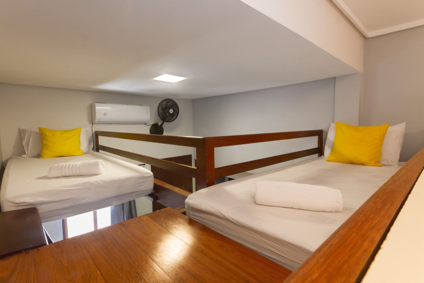 Um quarto com duas camas e um ventilador no teto.