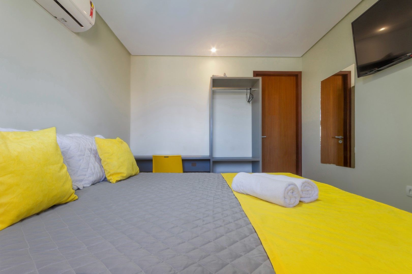 Um quarto com uma cama, televisão e um armário.