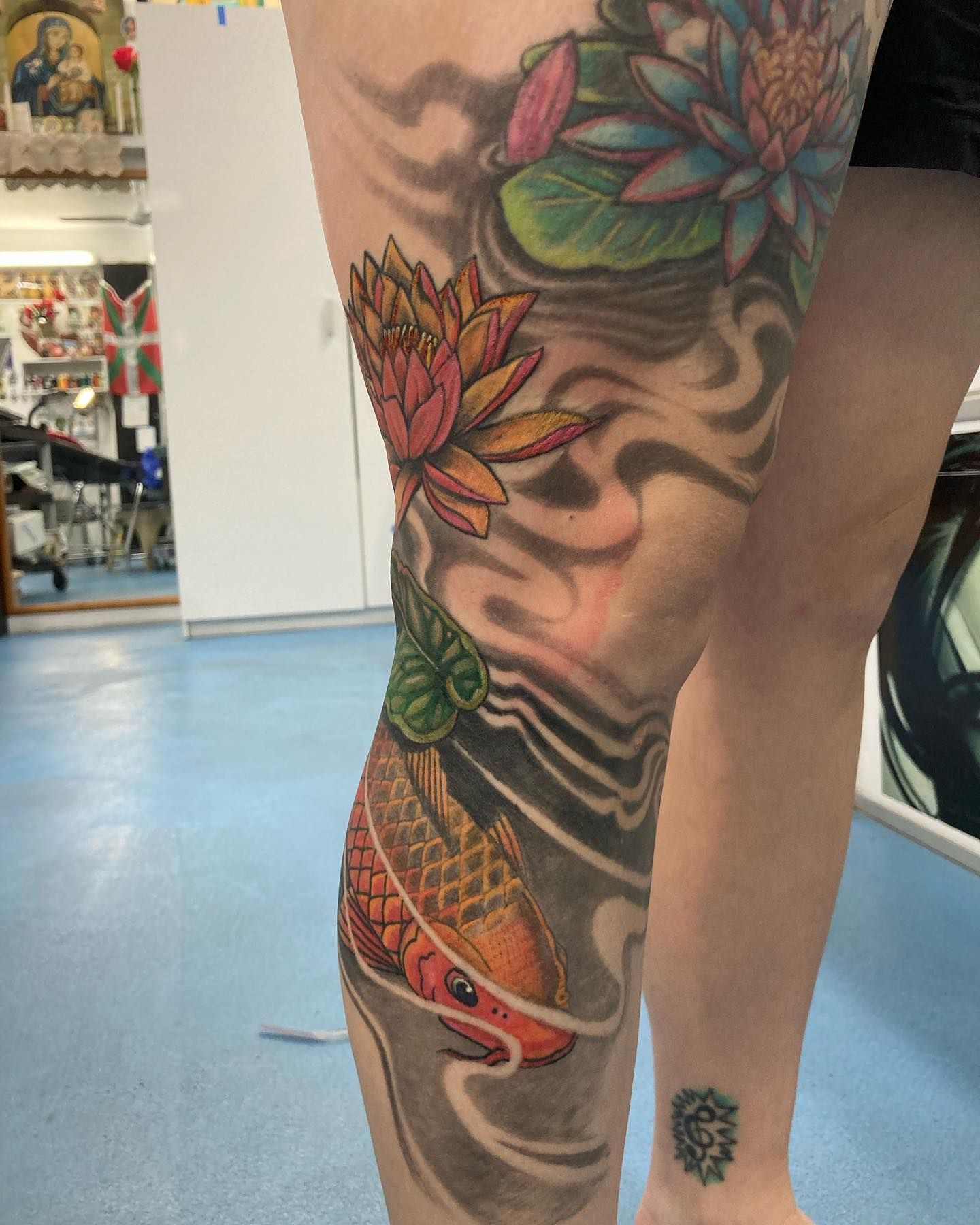 A Woman Has a Tattoo of a Fish and Flowers on Her Leg — La Bomba Loca Tattoo in Cairns City, QLD
