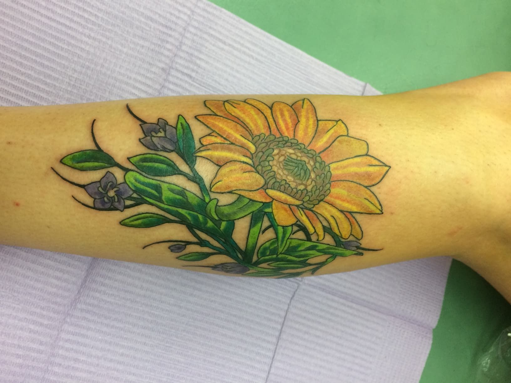 A Woman Has a Tattoo of a Sunflower on Her Arm — La Bomba Loca Tattoo in Cairns City, QLD