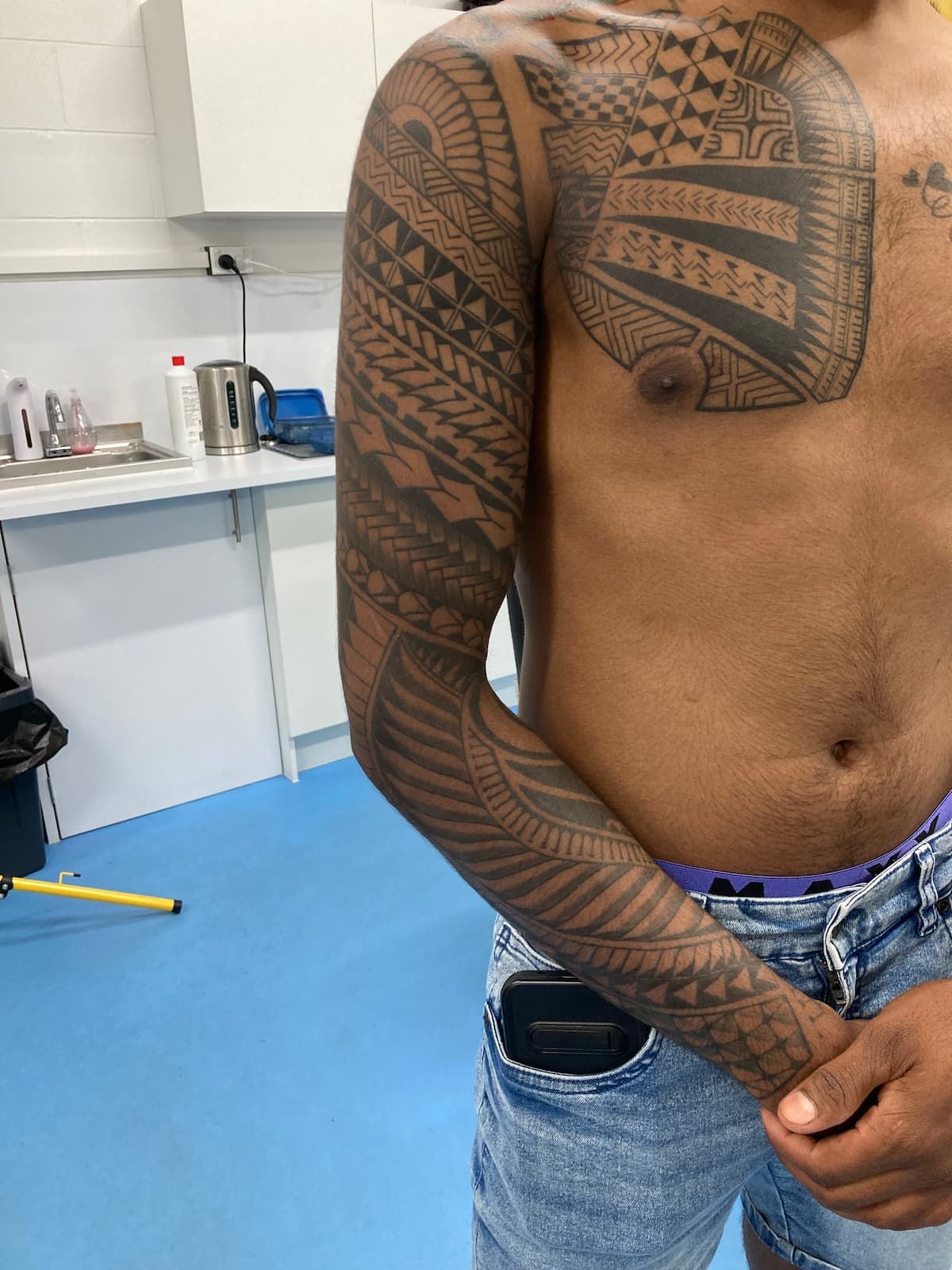 A Shirtless Man With a Tattoo on His Chest and Arm — La Bomba Loca Tattoo in Cairns City, QLD