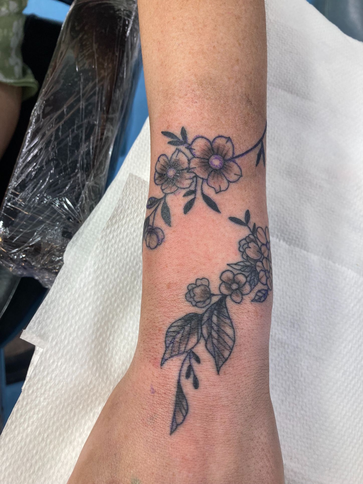 A Woman Has a Tattoo of Flowers and Leaves on Her Wrist — La Bomba Loca Tattoo in Cairns City, QLD
