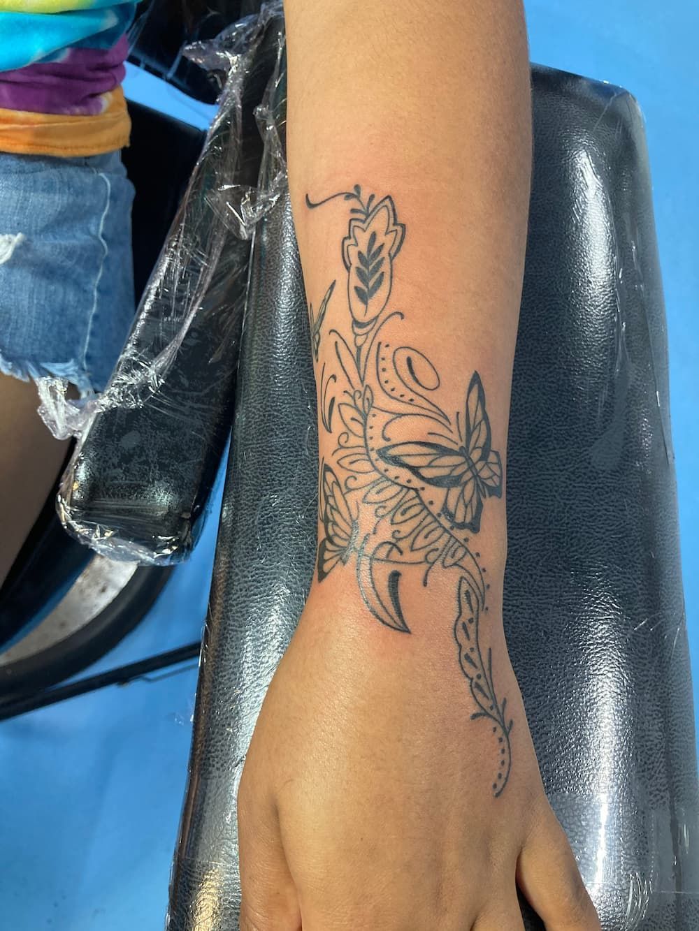 A Woman Has a Tattoo of Flowers and Butterflies on Her Wrist — La Bomba Loca Tattoo in Cairns City, QLD 