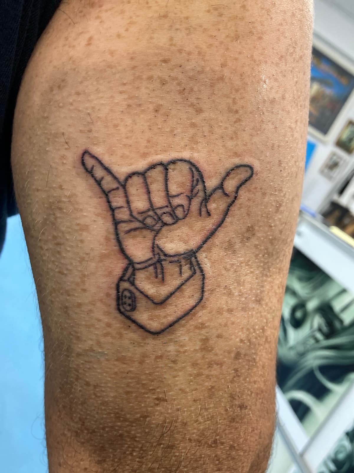 A Tattoo of a Hand Making a Hang Loose Sign on a Man's Arm — La Bomba Loca Tattoo in Cairns City, QLD
